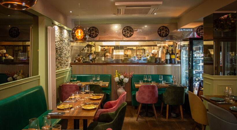 Dining tables, green banquette seating and the bar at Mila Loughton